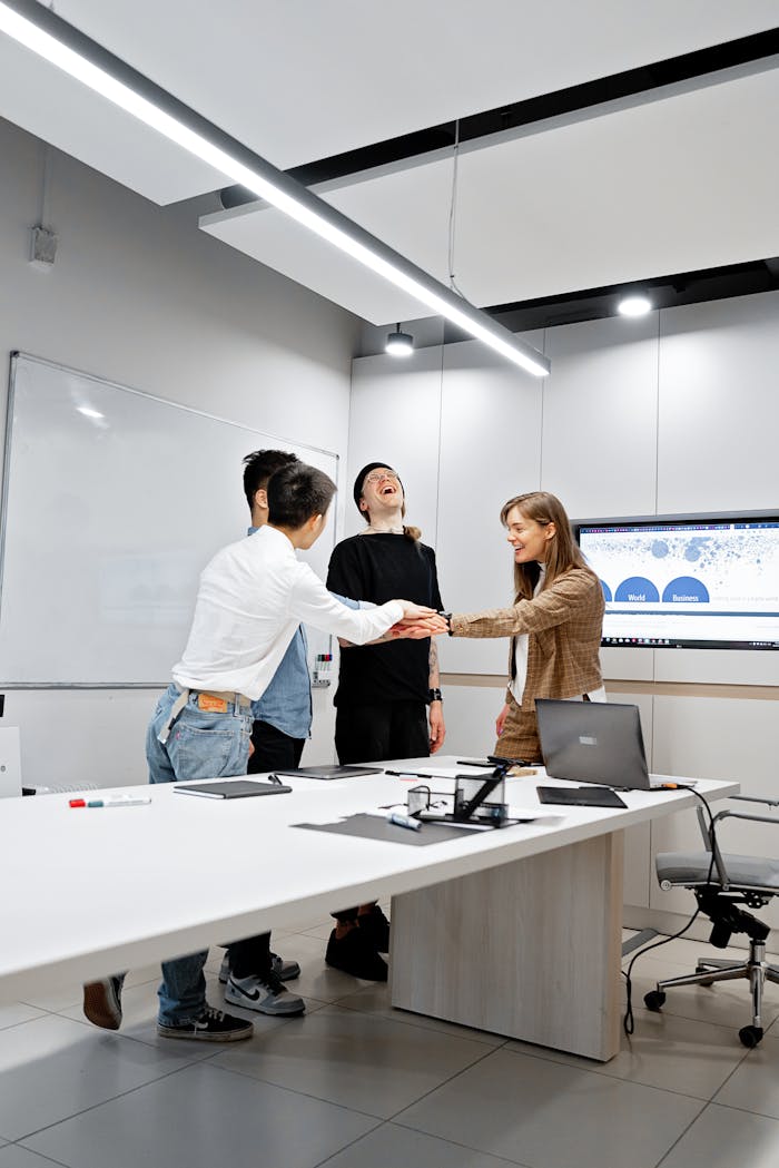 Group of diverse coworkers sharing a spirited moment in a sleek office environment, emphasizing teamwork.